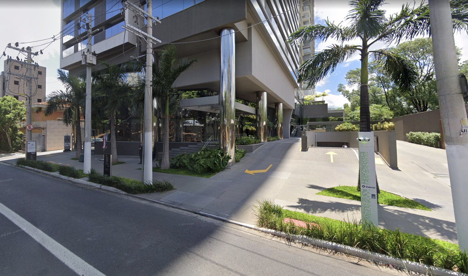 Av. Rubem Berta: a entrada do estacionamento fica ao lado da placa branca com o número 850, marcada com a seta na foto.